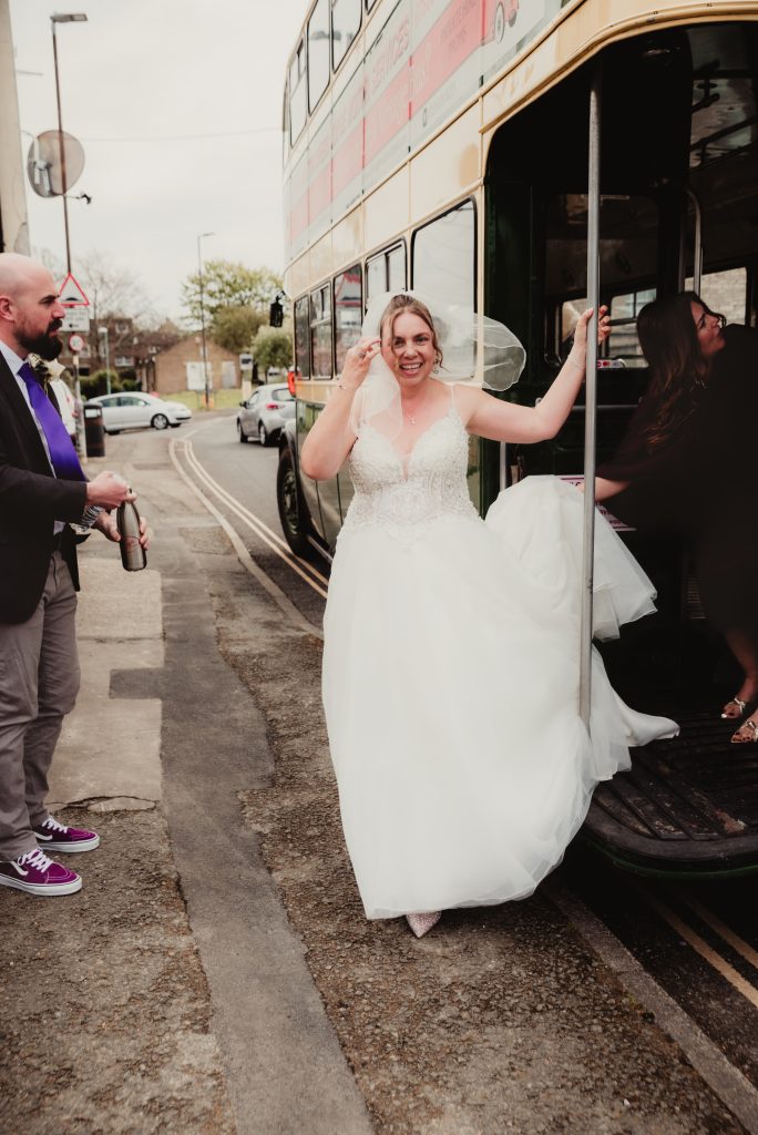 Bride stepping off a vintage bus at Stroud Registry Office – Gloucestershire candid wedding.
