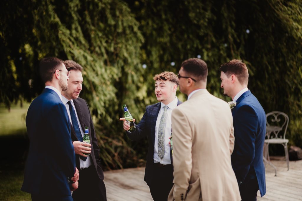 Guests enjoying the sunny drinks reception beside the lake at Barns and Yard wedding venue