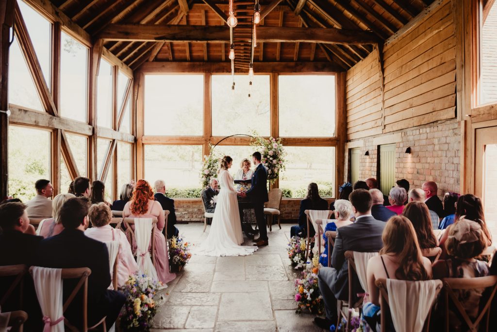Bride and groom exchanging vows in the beautifully rustic barn ceremony space at Barns and Yard