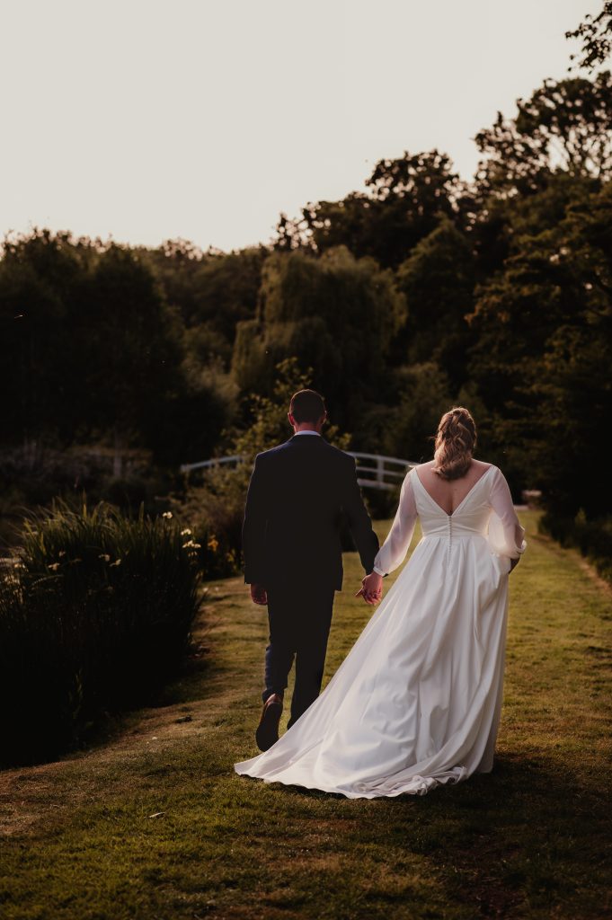 The bride walking hand in hand with the groom during golden hour at Barns and Yard Worcestershire