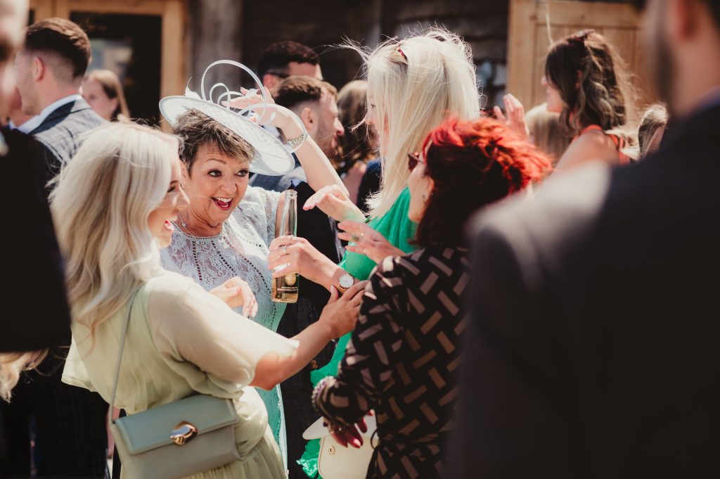 Guests enjoying a relaxed drinks reception in the courtyard at Upcote Barn, photographed by Gloucestershire wedding photographer