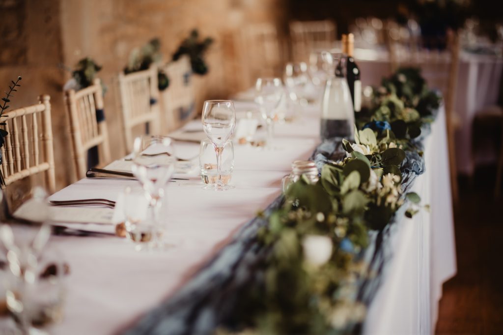 Table decor featuring vintage gin bottles and wildflowers at a Cotswold barn wedding
