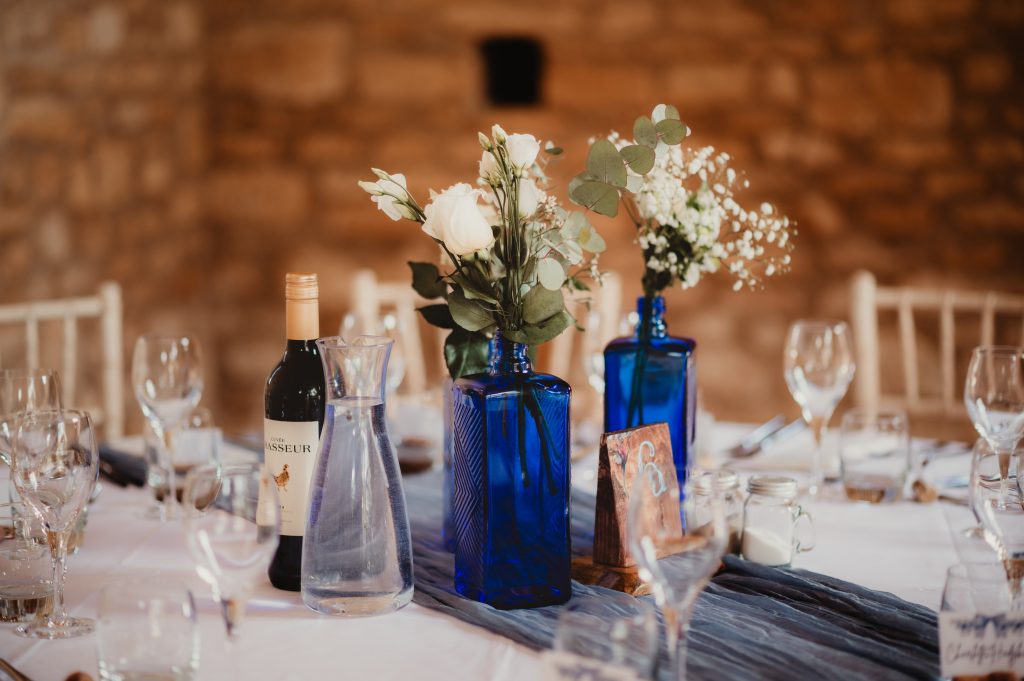 Detail shot of gin bottle centrepieces at this stylish Gloucestershire wedding