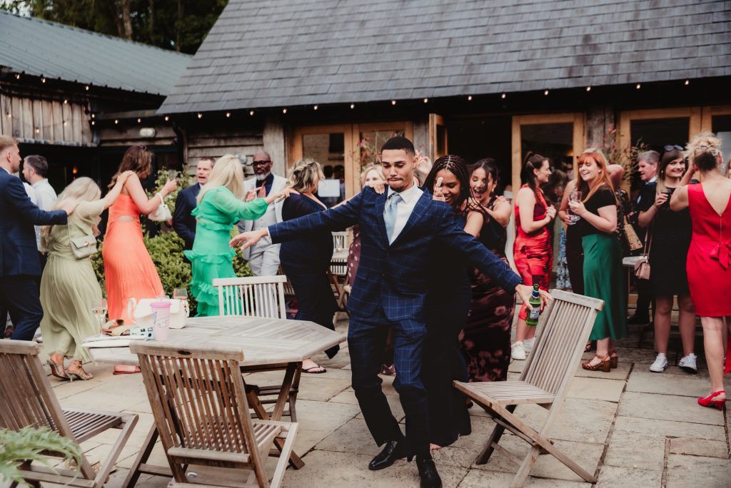 Fun and spontaneous conga line in the courtyard during wedding room turnaround at The Barn at Upcote
